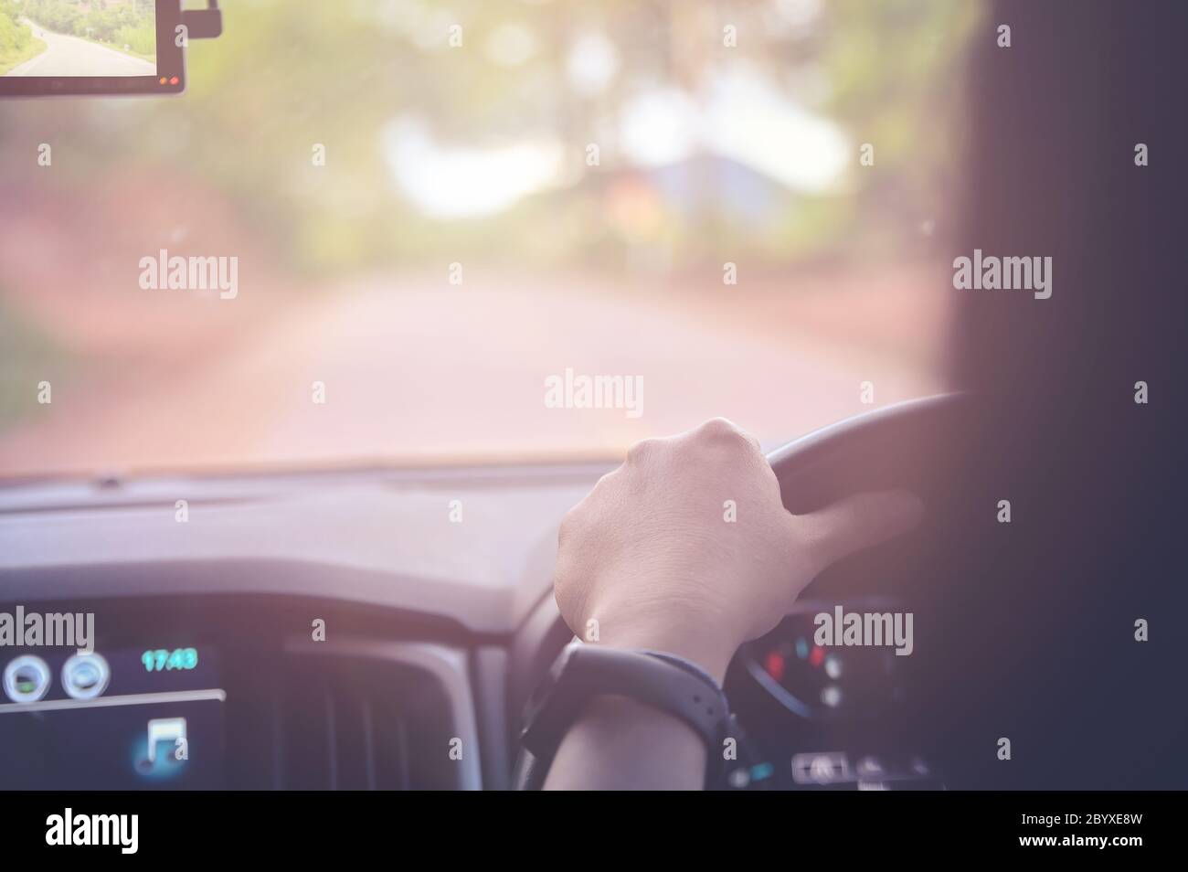 Hands on wheel, Close up woman driving car on road with sunlight warm tone for come back to home Stock Photo