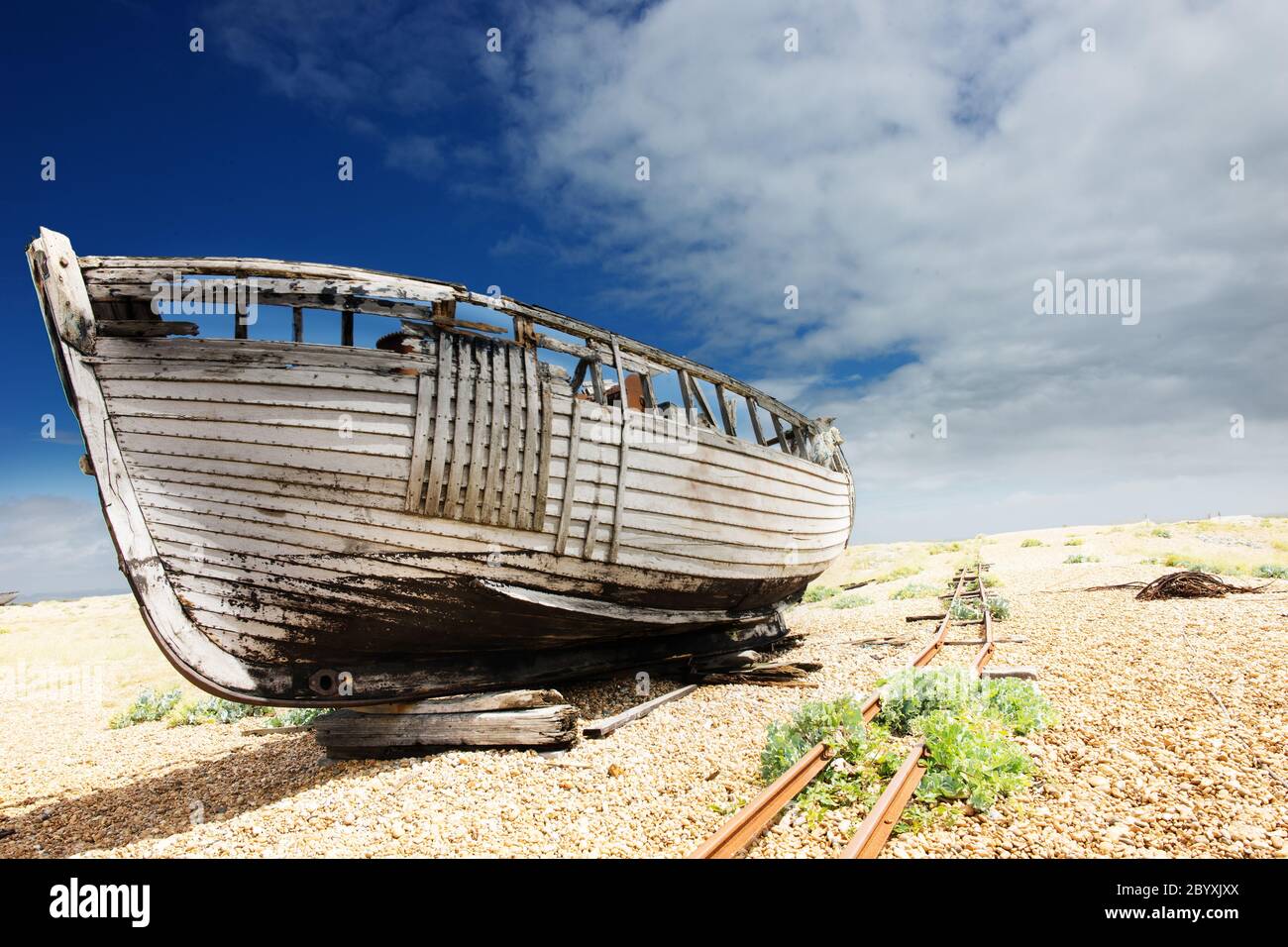 wooden fishing boat left to rot and decay on the shingle beach at