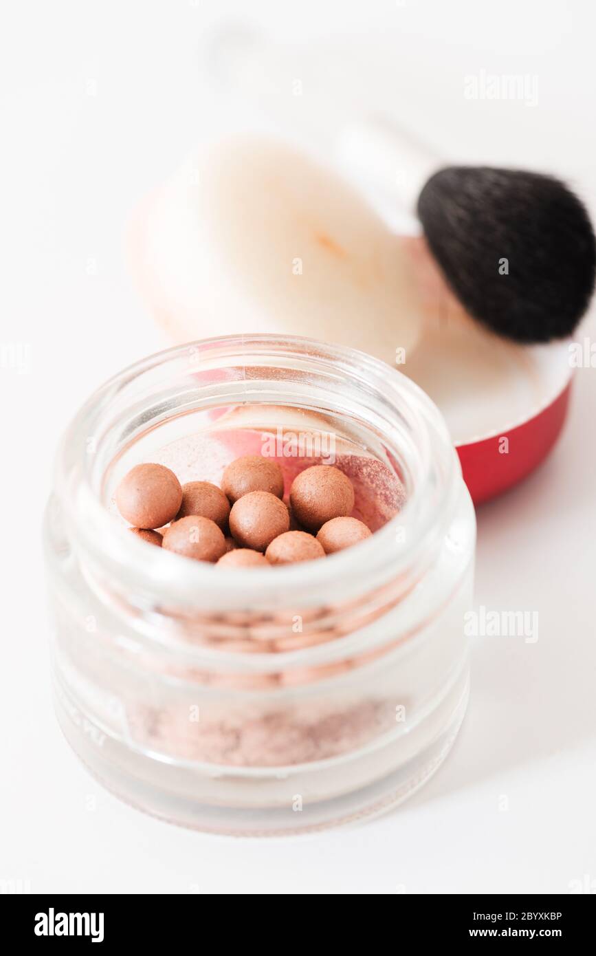 Composition of bronzing pearls and makeup brush vertical Stock Photo