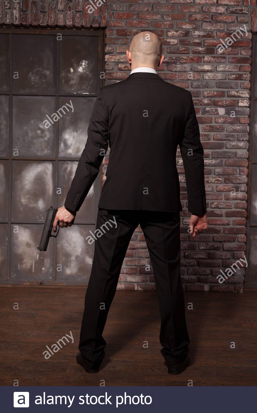 Contract Murderer With Gun Wallpaper Concept Back View Bald Assassin In Suit Holds Weapon In Hand Secret Agent On Mission Stock Photo Alamy