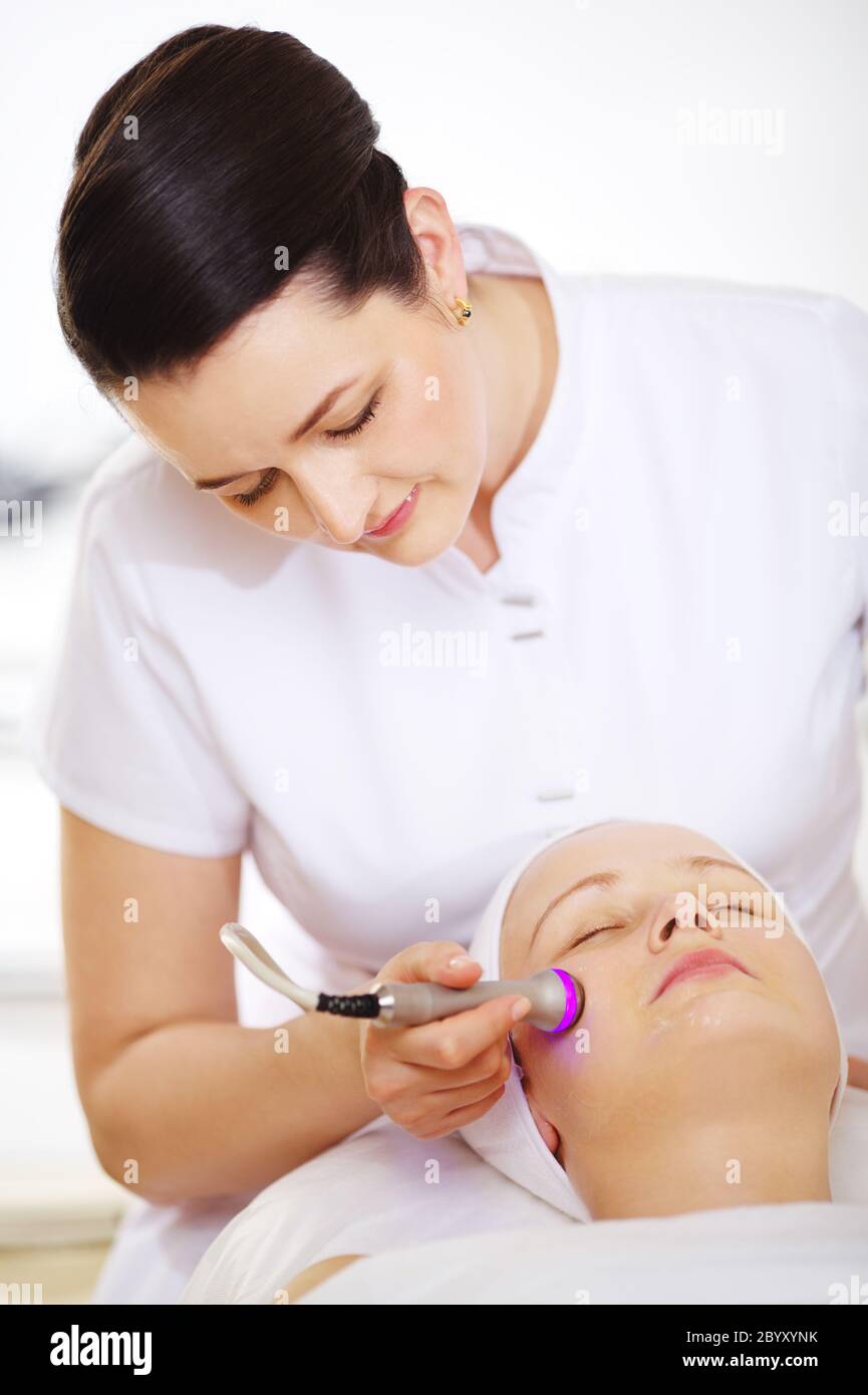 Cosmetician providing lifting procedure with special equipment Stock Photo