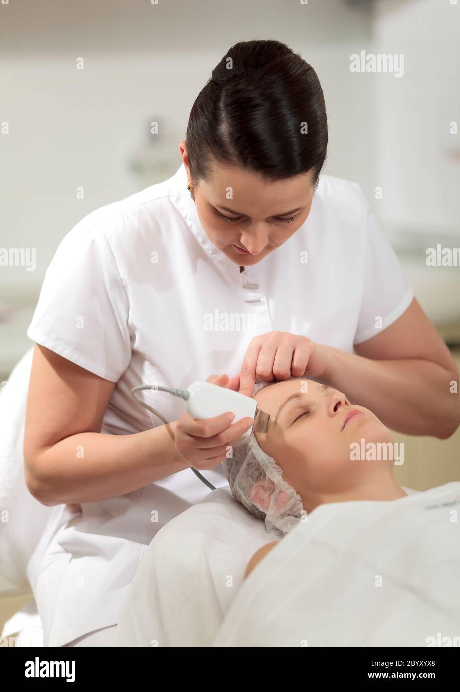 Cosmetician providing ultrasonic facial cleaning Stock Photo