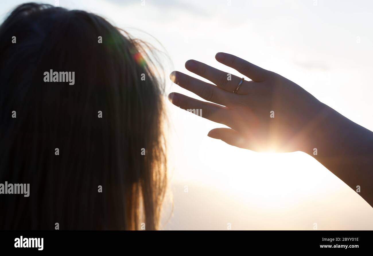 Woman hiding from the sun with hand Stock Photo