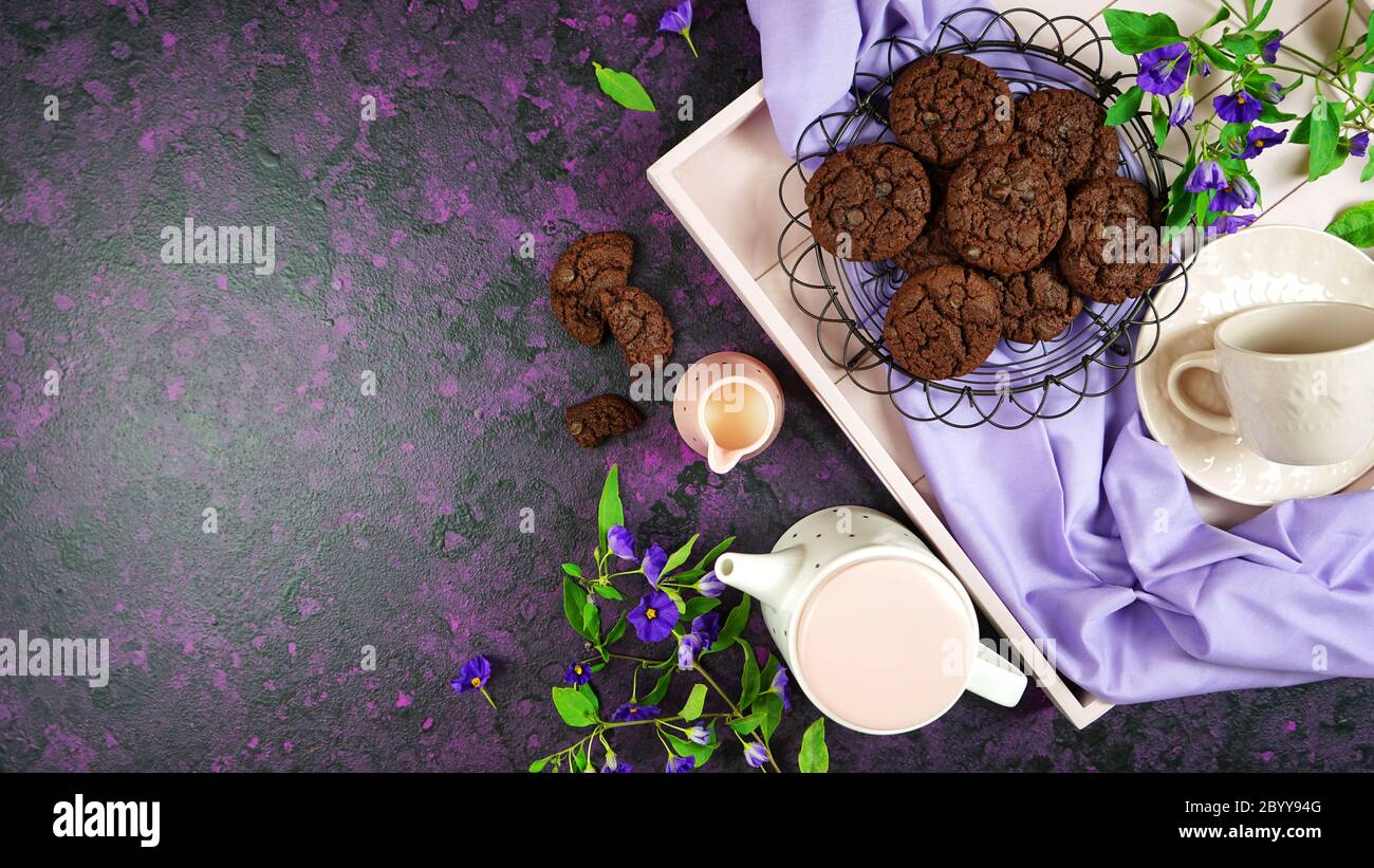 Serving freshly baked double chocolate chip homemade cookies on pink tray with tea and coffee, creative concept flat lay. Top view overhead with negat Stock Photo