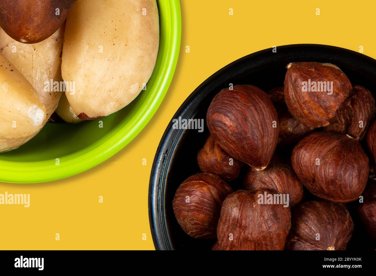 Bowl with hazelnut and Brazil nuts on a yellow background. Seen from