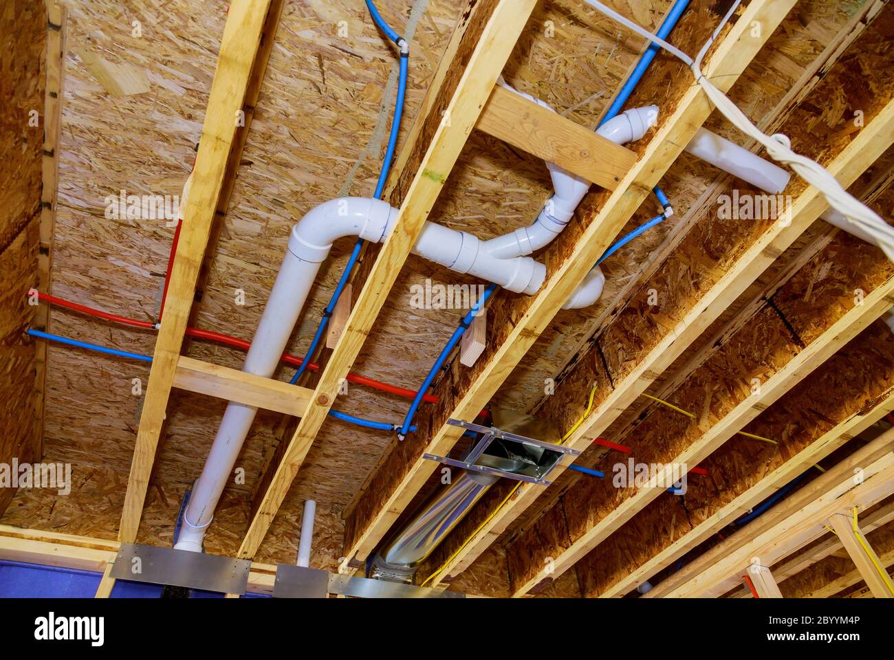 Home construction with hot red and cold blue pex pipe layout in pipes and exposed beams Stock