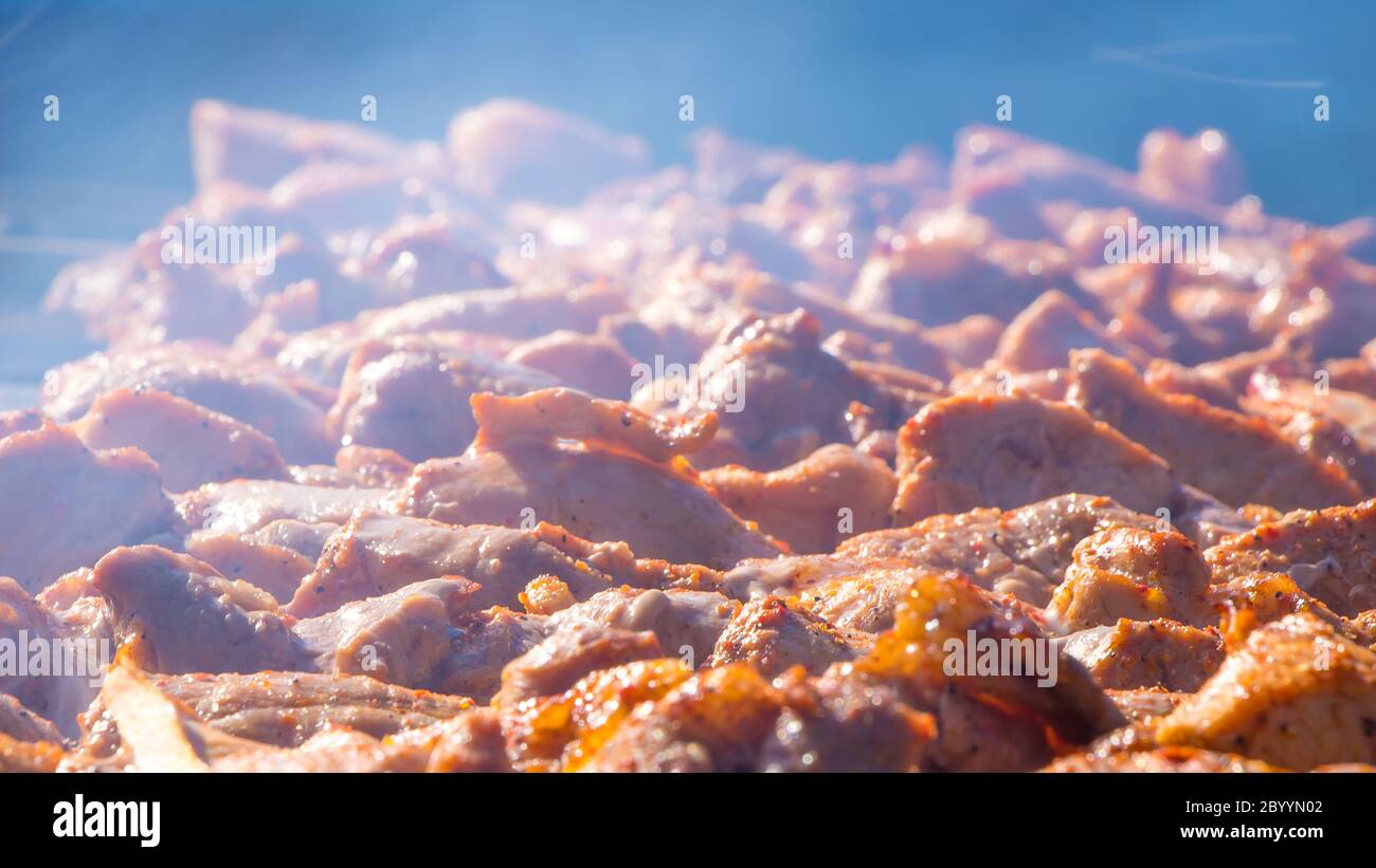 Fresh meat dressed on skewers is fried on a roaster or grill. The chef prepares meat in a cafe