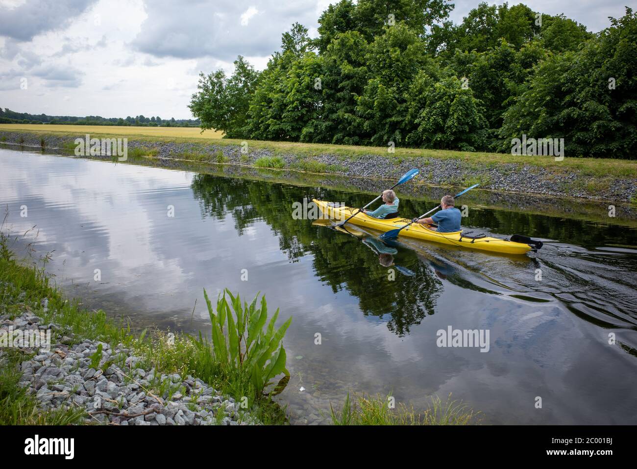 two canoeists sitting in a canoe and paddling on a canal Stock Photo