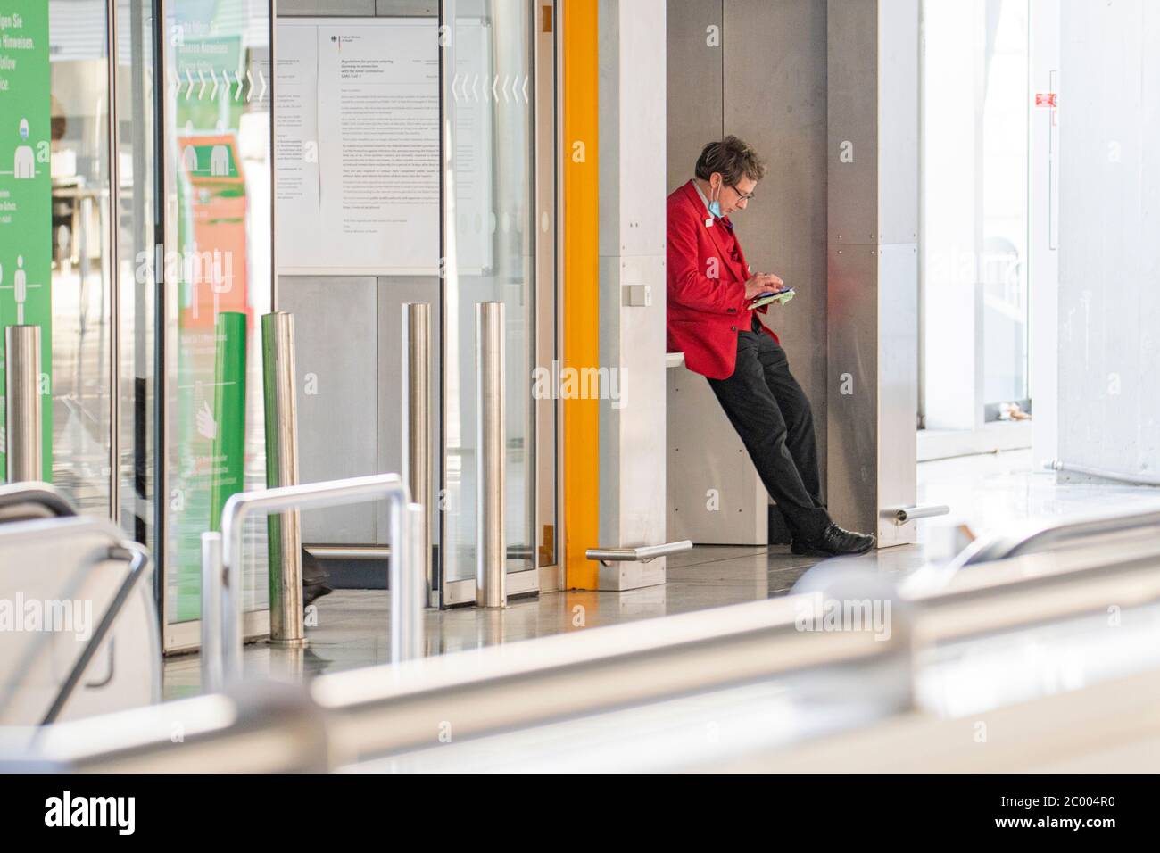 An airport worker in the check-in area at the nearly empty Frankfurt International Airport during the lockdown caused by the COVID-19 virus. Worldwide, the air traffic industry is heavily impacted by the massive drop in traffic. Stock Photo