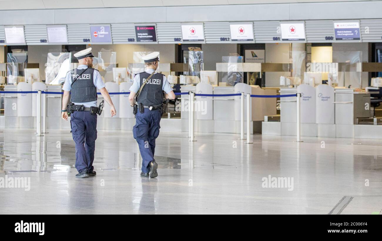 Airport police patrolling the check-in area at the nearly empty Frankfurt Airport during the lockdown caused by the COVID-19 virus. Worldwide, the air traffic industry is heavily impacted by the massive drop in traffic. Stock Photo