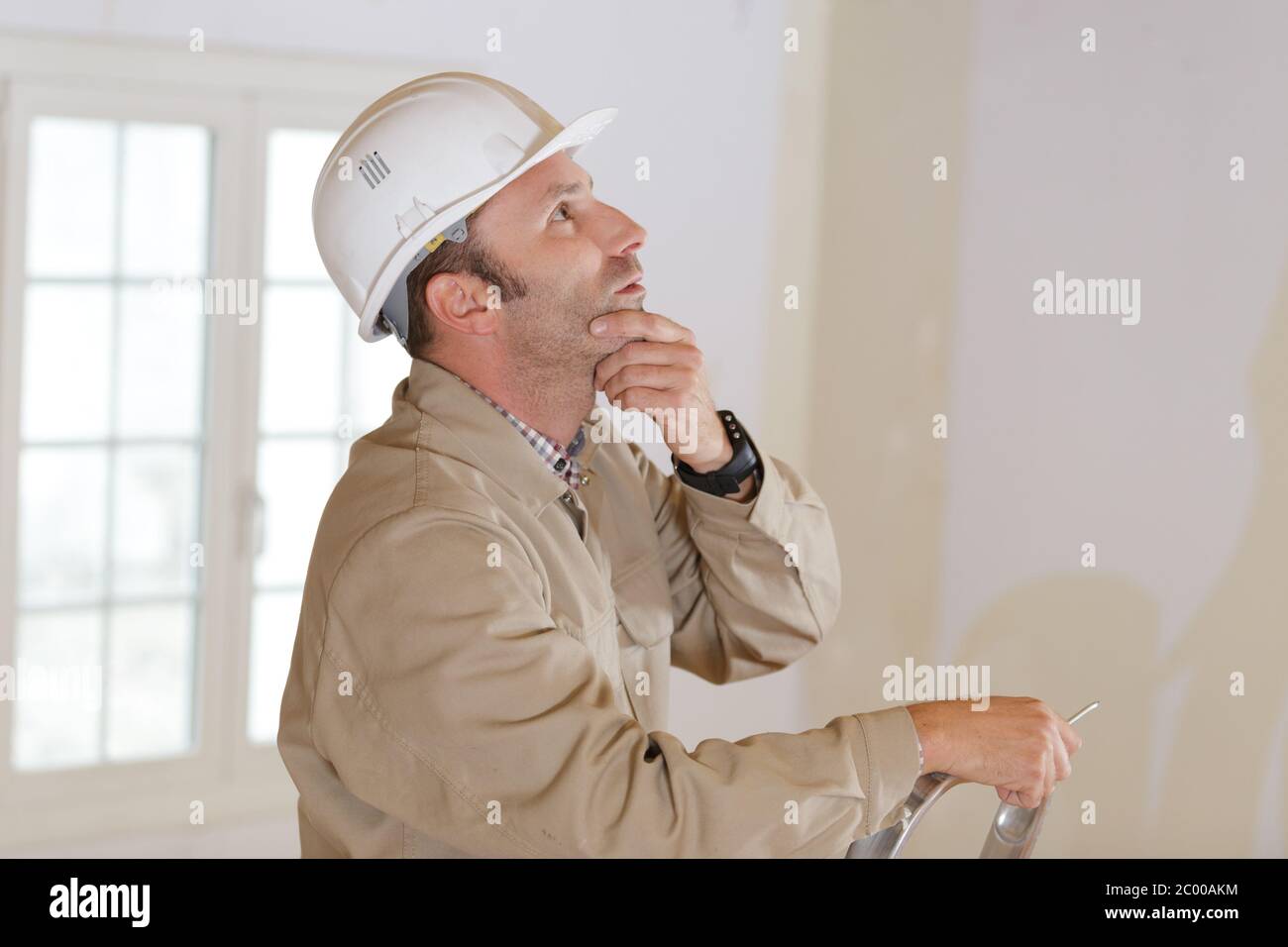 builder thinking about something while holding clipboard Stock Photo
