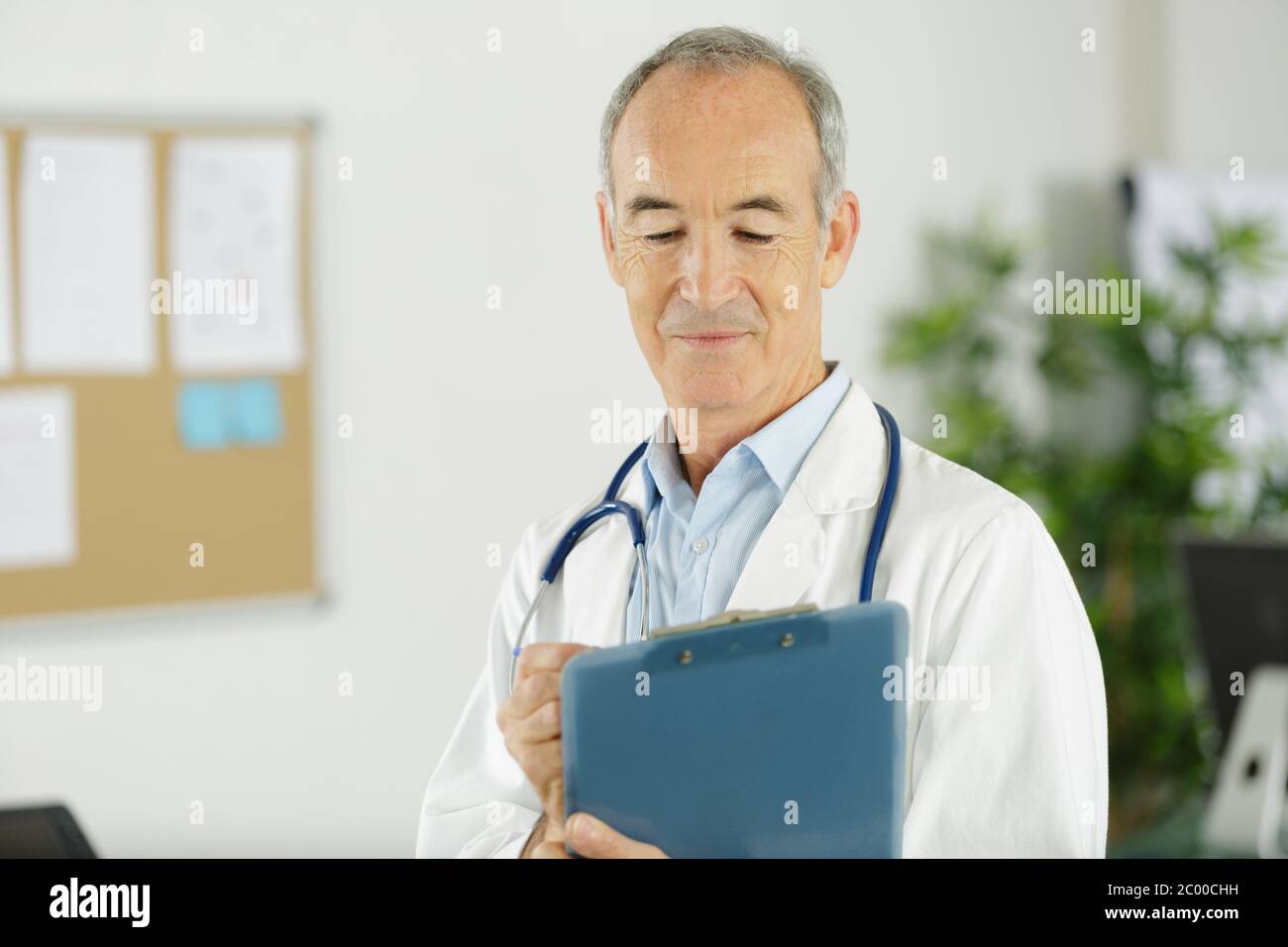 senior male doctor writing on clipboard Stock Photo