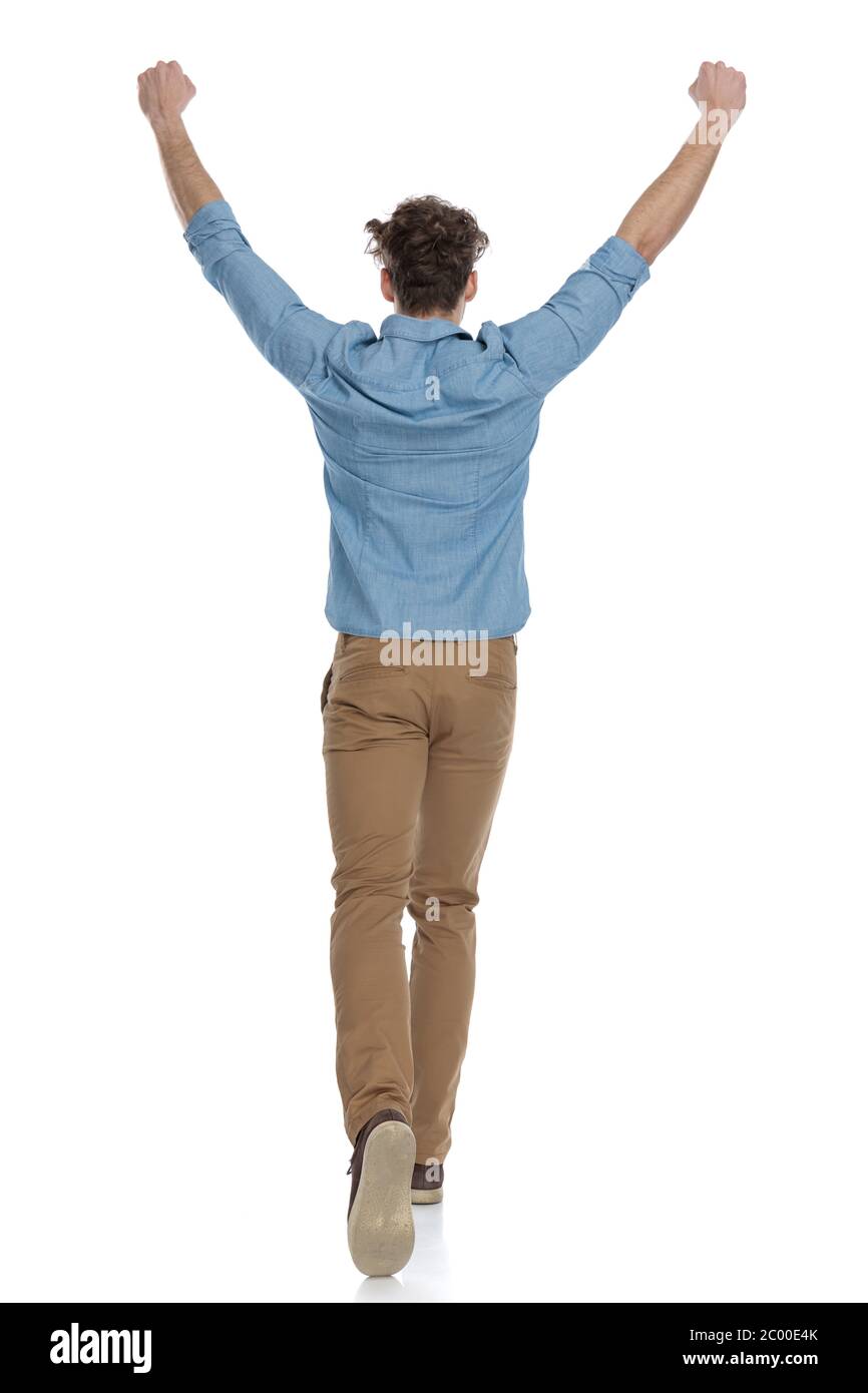 back view of enthusiastic guy holding arms in the air and cheering