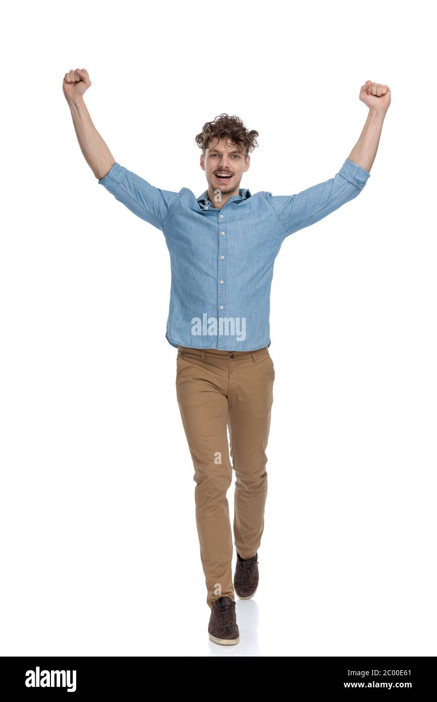 excited young man holding arms in the air and cheering, walking