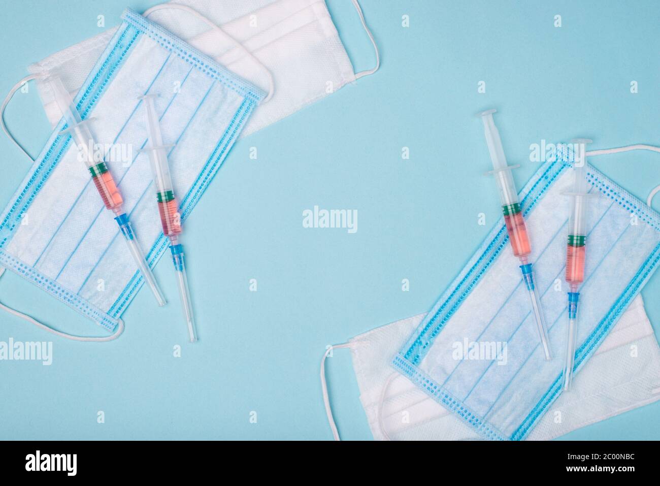 Corona outbreak concept. Top above overhead view photo of shots with red liquid placed on top of masks making center empty isolated on blue background Stock Photo