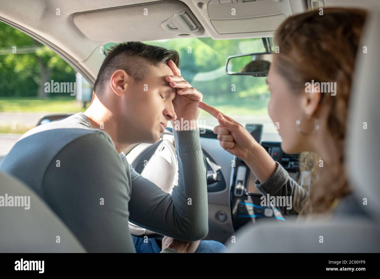 Tired man with closed eyes driving car and next to woman Stock Photo