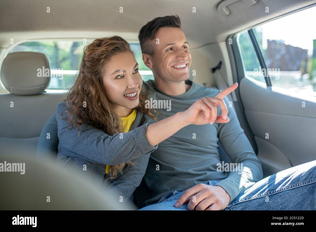 Woman showing hand out window and hugging her man in car Stock Photo