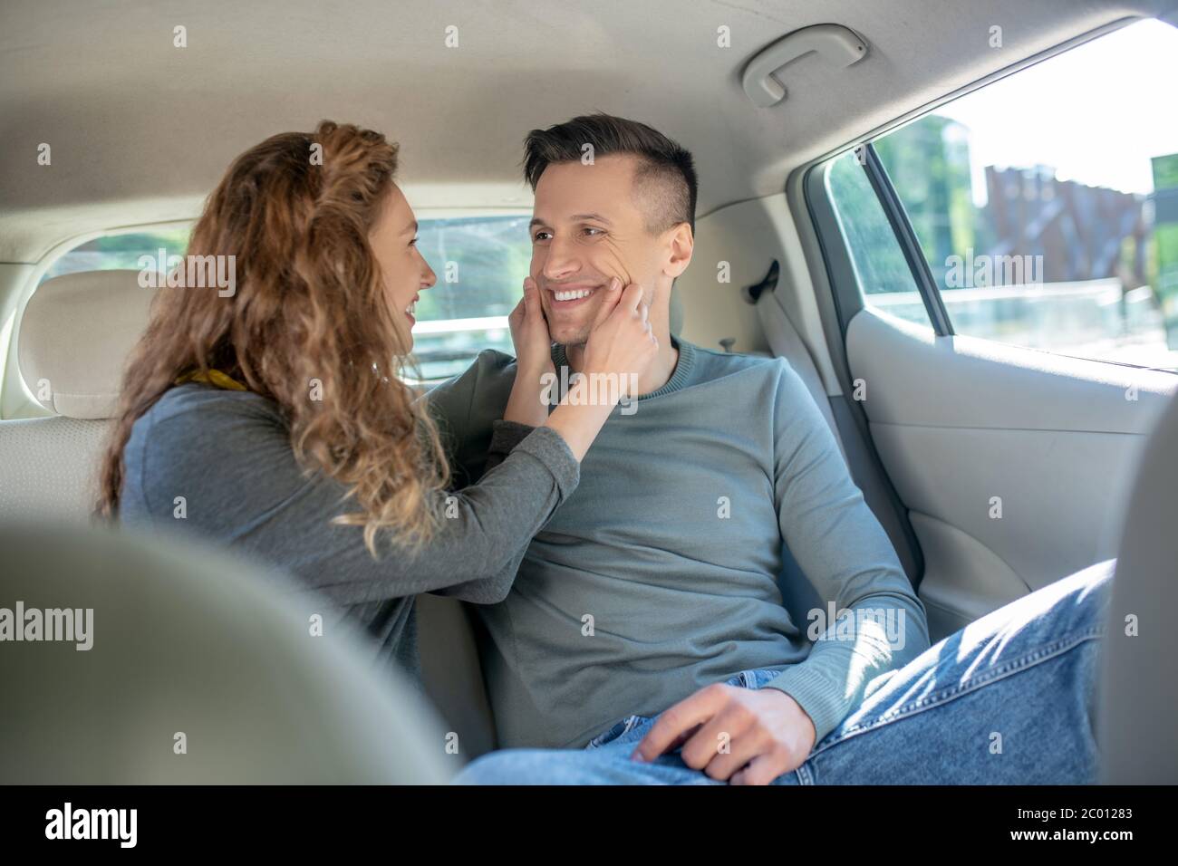 Cheerful pretty woman touching smiling mans face Stock Photo