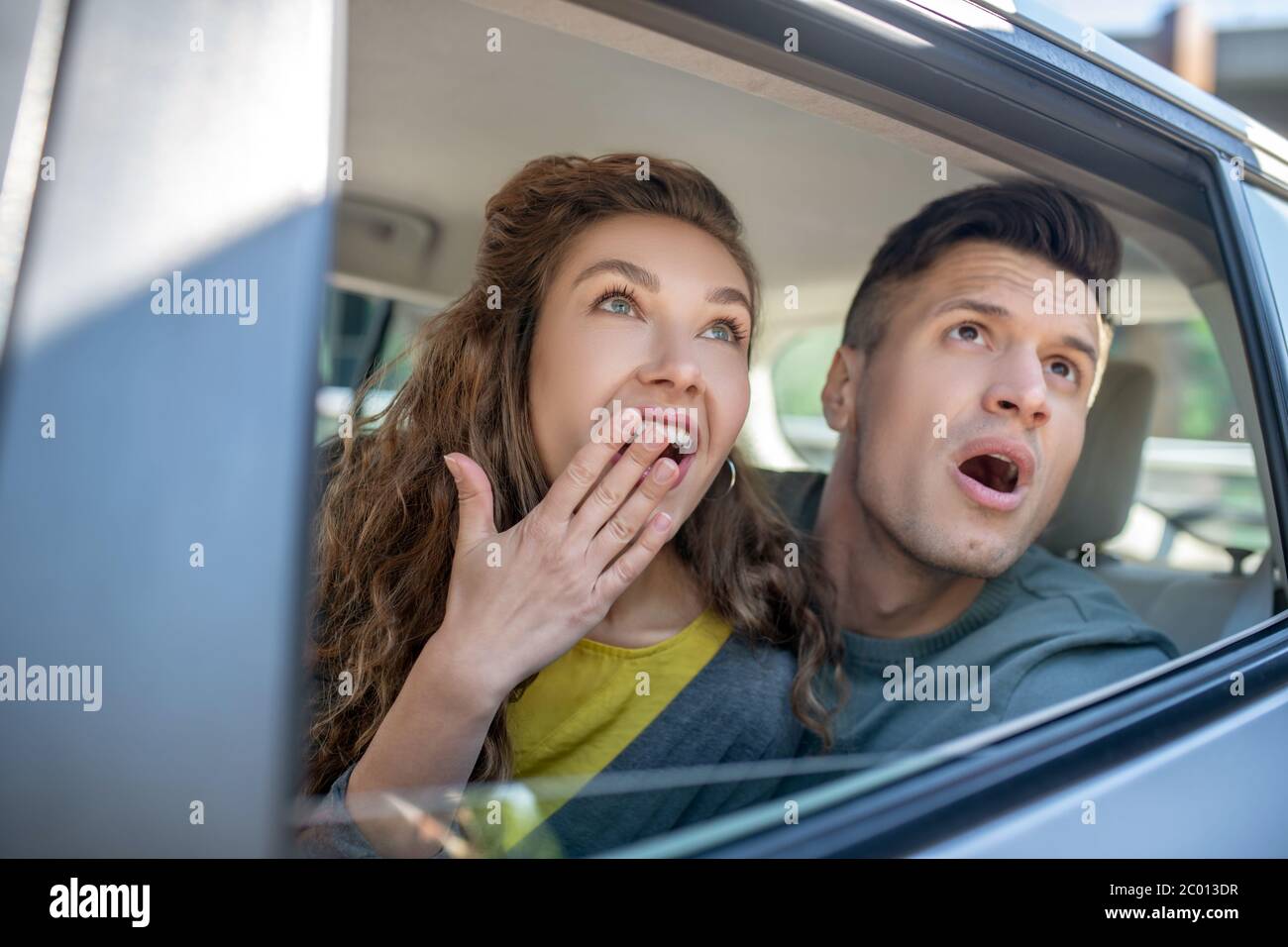 Very surprised man and woman looking out of the car. Stock Photo
