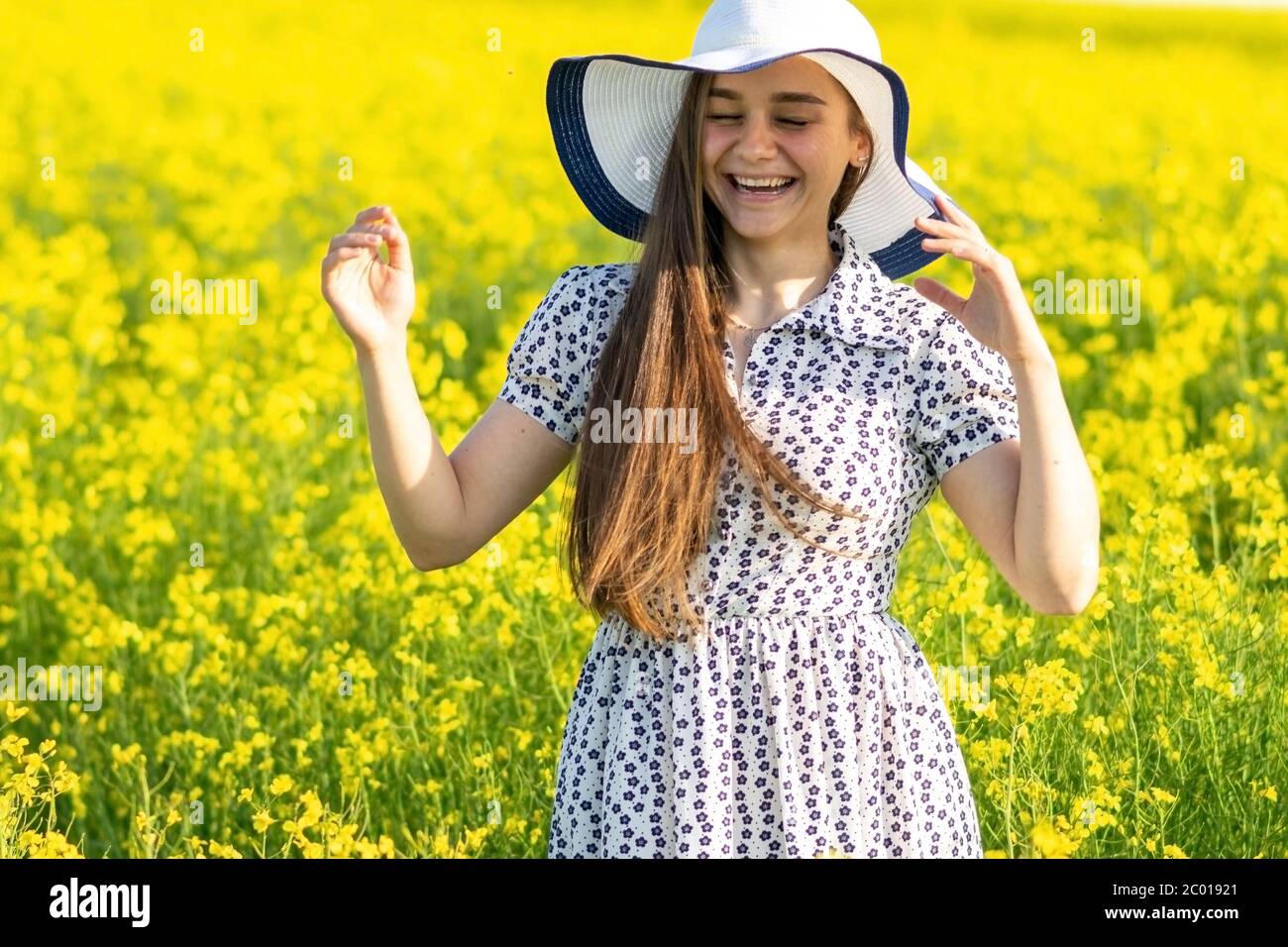 Beautiful girl in a rapeseed field, in a dress and hat Stock Photo - Alamy