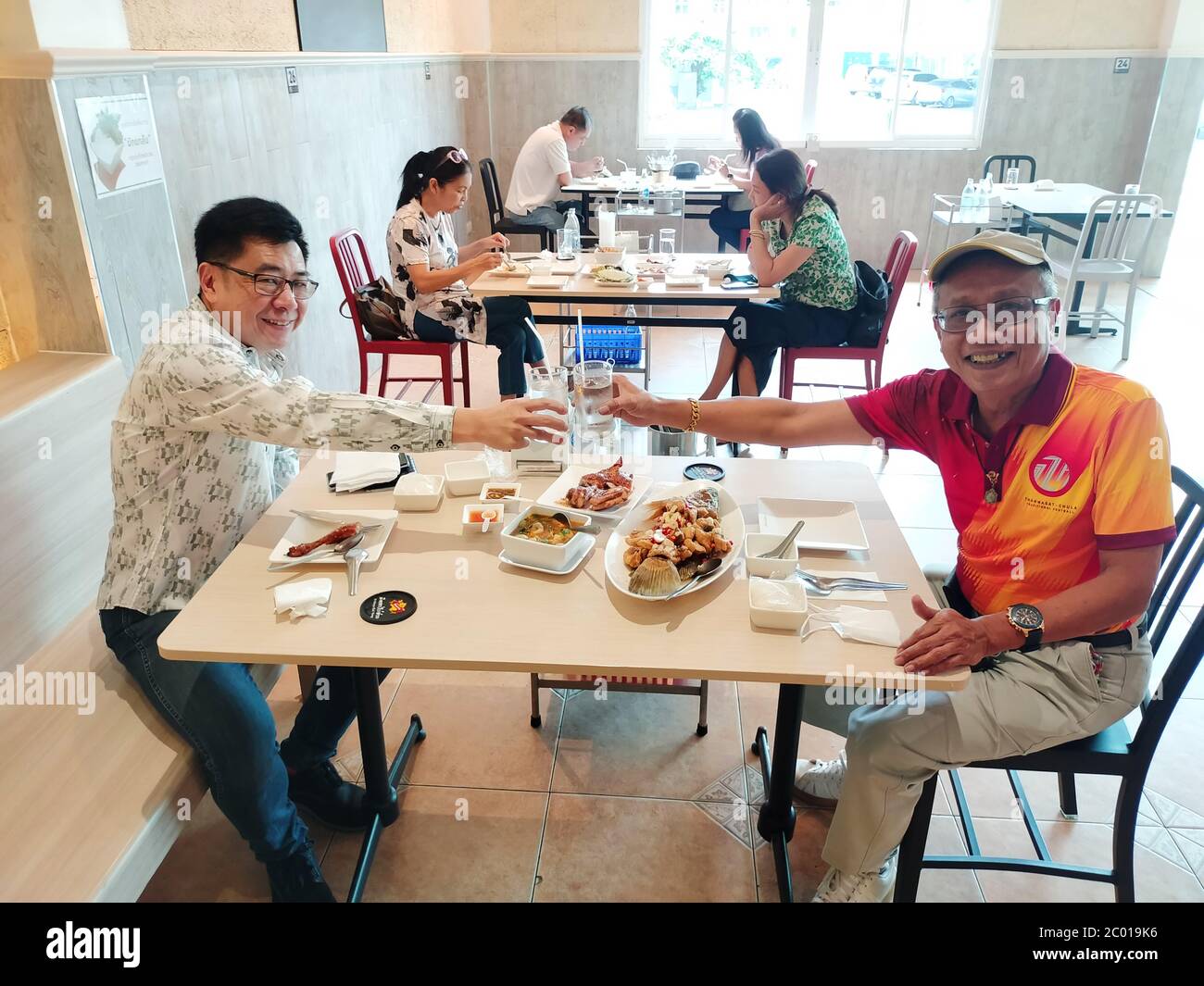Two friends have a social distancing during lunch in a restaurant Stock ...