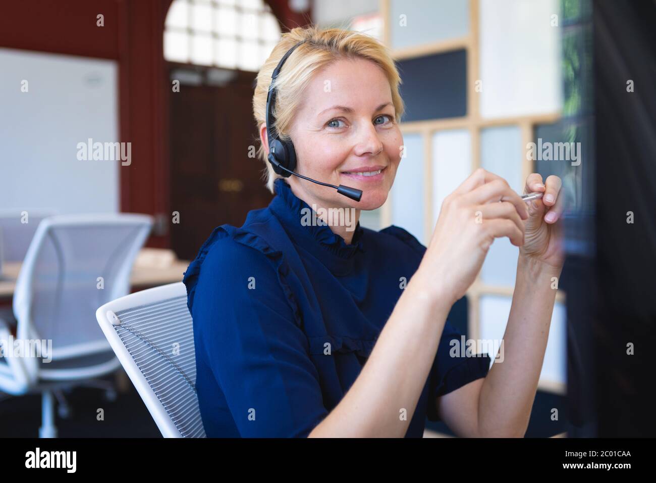 Blonde woman with an earpiece on smiliing and looking at camera Stock Photo
