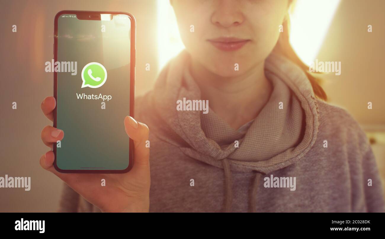 KYIV, UKRAINE-JANUARY, 2020: Whatsapp on Mobile Phone Screen. Young Girl Showing Smartphone Screen with Whatsapp on it while Looking at the Camera. Focus on Smartphone. Stock Photo