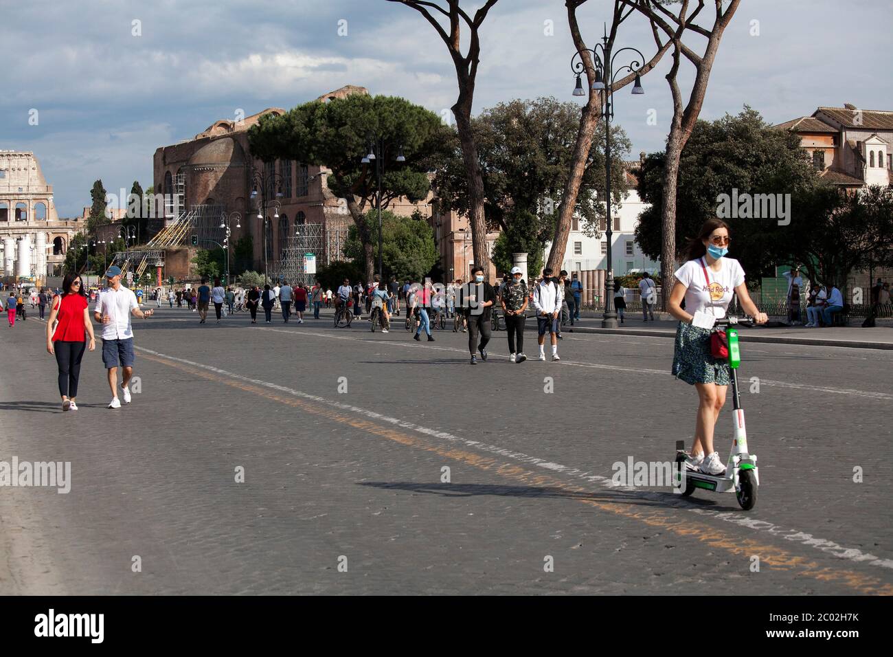 A woman wearing a protective face mask uses a electric scooters to commute in Via dei Fori Imperiali near Piazza Venezia in central Rome on June 02, 2020 as Italy starts to ease its lockdown, during the country's lockdown aimed at curbing the spread of the COVID-19 infection, caused by the novel coronavirus. The electric scooters of the American company Lime. Stock Photo