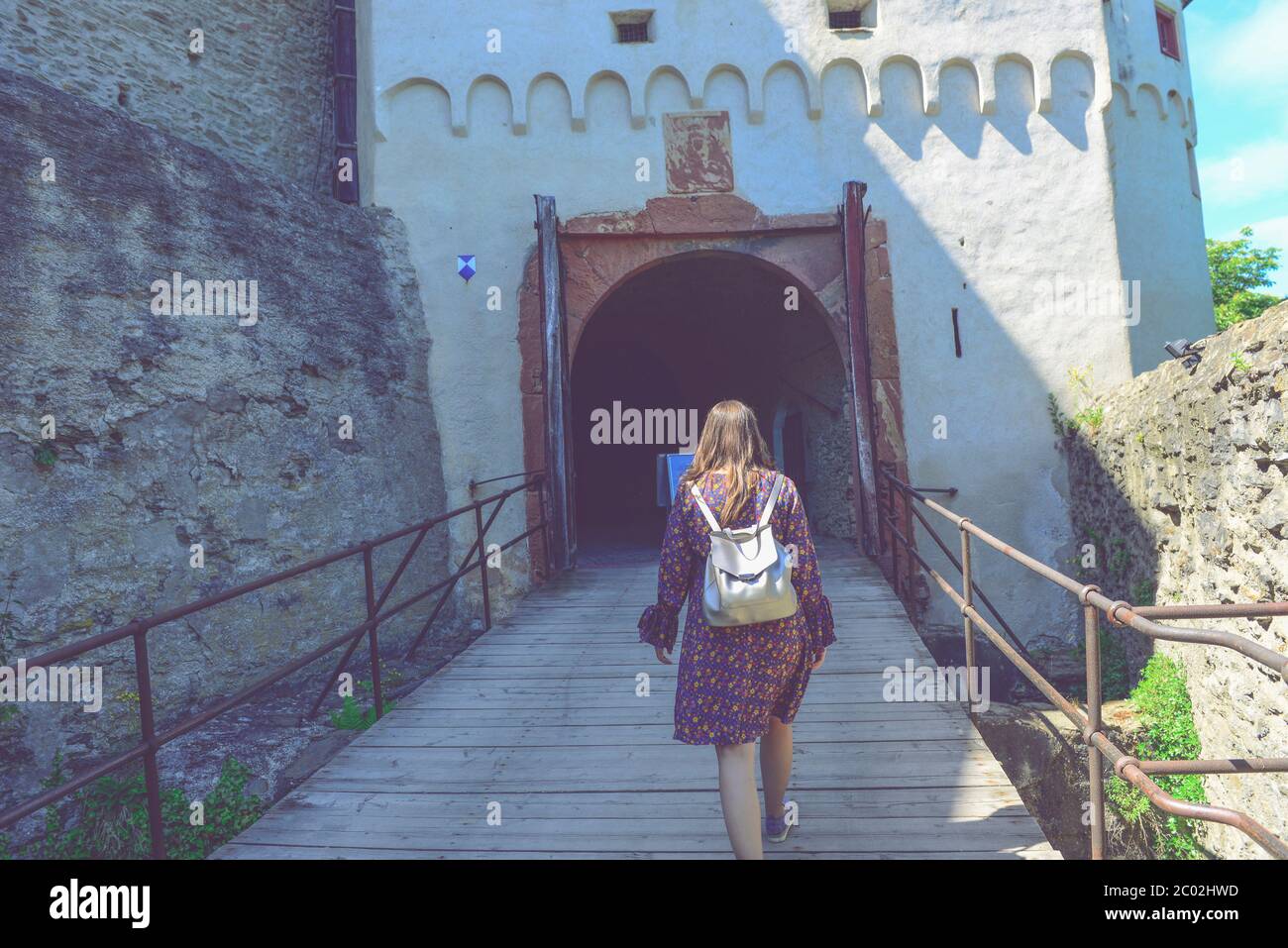 Woman walking on a bridge to an old fortress, entrance to the fortified citadel Stock Photo