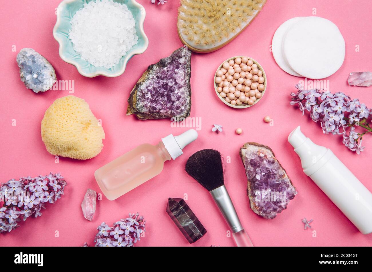 Above top down view of various white cosmetic and beauty products containers with lilac (Syringa) blossoms and semi precious amethyst crystal clusters Stock Photo