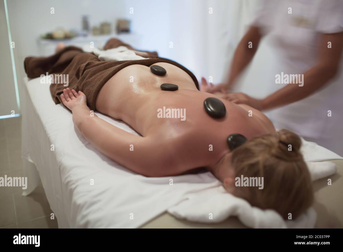 Woman during hot stone therapy at beauty spa Stock Photo