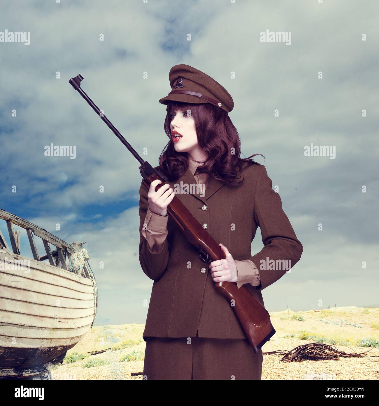Attractive woman in army uniform carrying a rifle Stock Photo