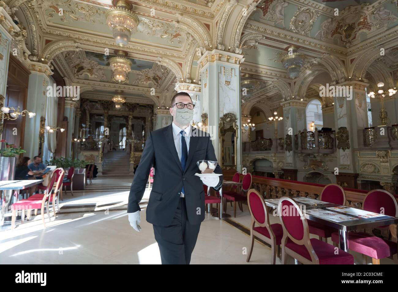(200611) -- BUDAPEST, June 11, 2020 (Xinhua) -- A waiter is seen serving customers at the reopened New York Cafe in Budapest, Hungary on June 10, 2020. Customers are allowed to enter the inside of cafe bars as the novel coronavirus pandemic has subsided and the COVID-19 restrictions were gradually lifted in Hungary. (Photo by Attila Volgyi/Xinhua) Stock Photo
