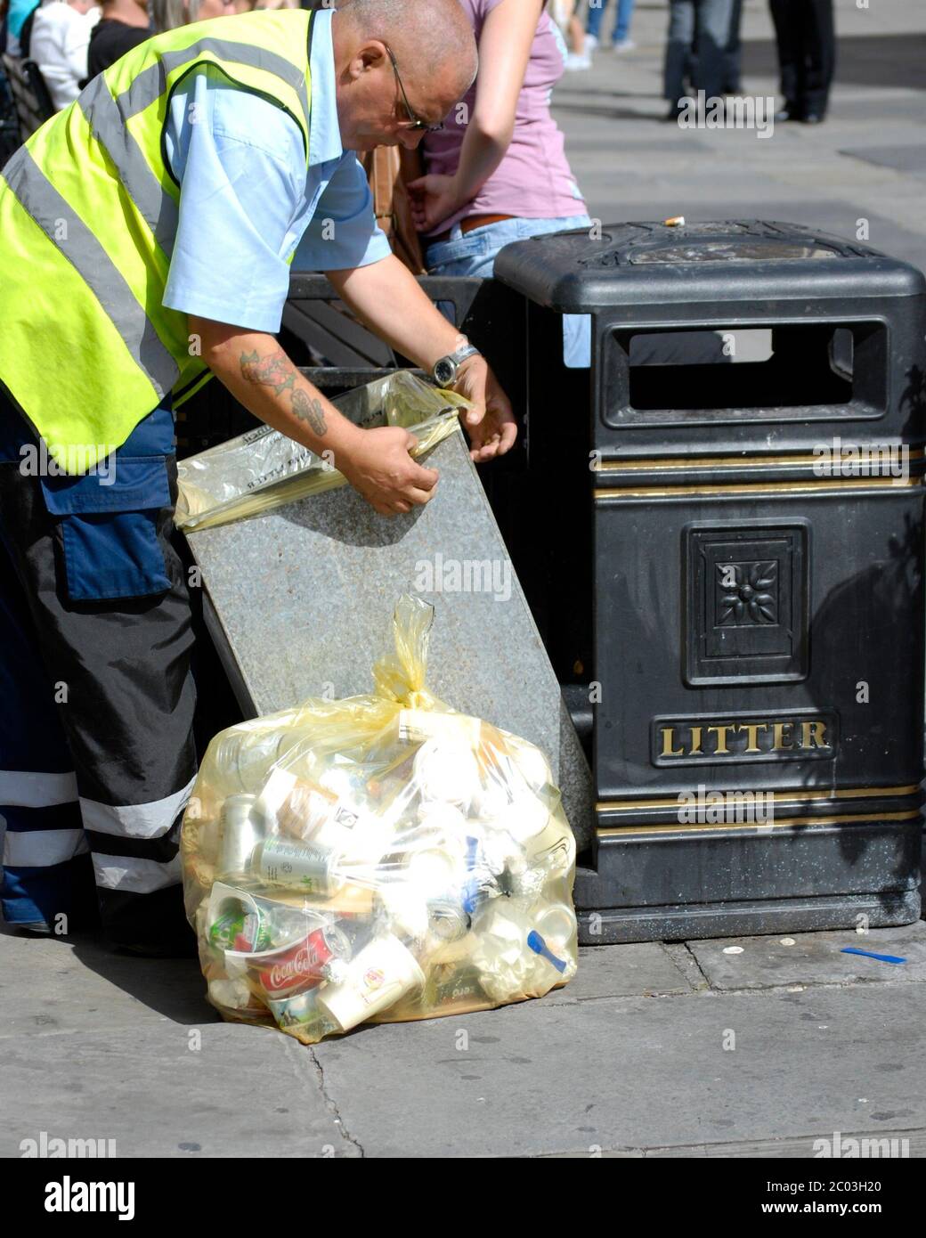 Local Authority Council worker empties public waste bin and fits new bin liner. Stock Photo