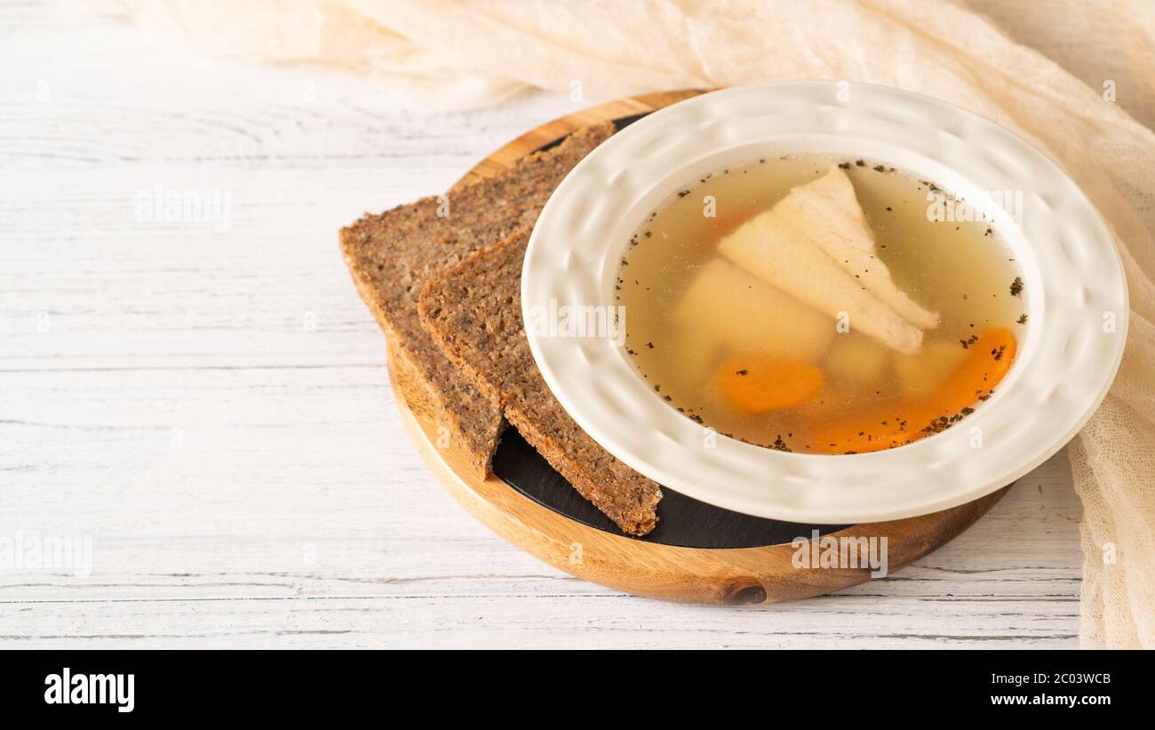 Fish soup in white bowl with wholemeal bread on white table. Potato, carrots, river trout fish soup. Ready to eat Stock Photo