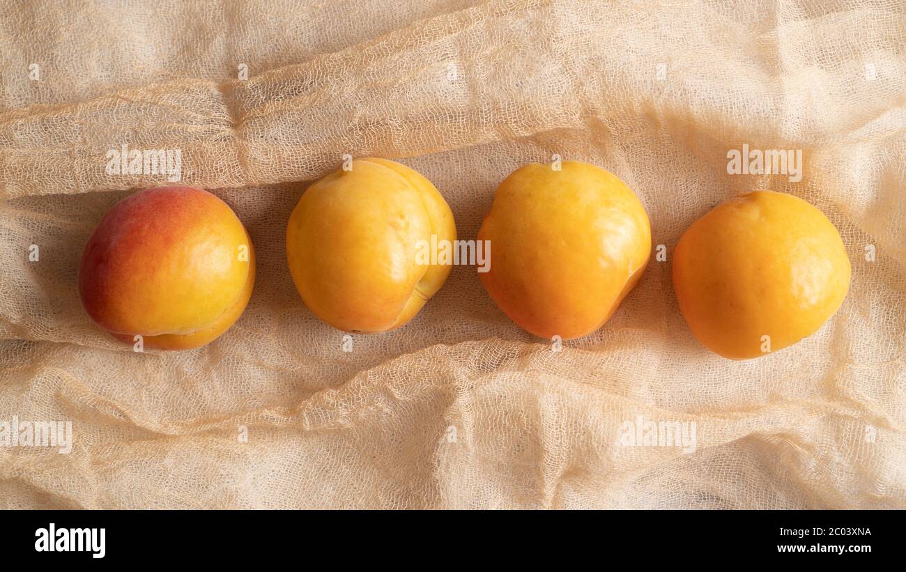 apricots on a soft and light fabric. a few apricots. bunch of apricots from garden. Yellow apricots on table cloth Stock Photo