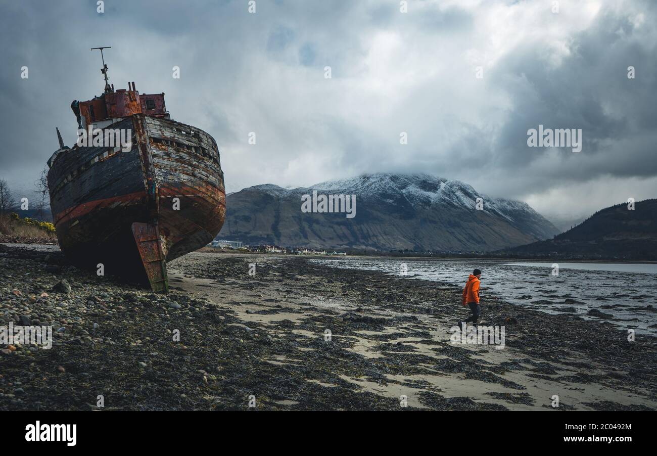 Ship wreck on the beach at low tide. The Old Boat of Corpach, Ben Navis on Loch Eil near Fort William in Scotland. Stock Photo