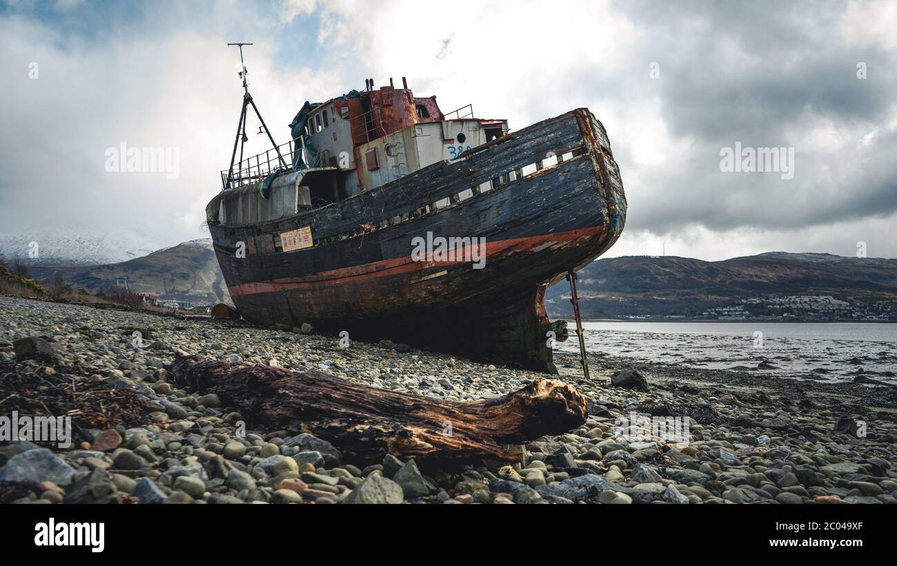 Ship wreck on the beach at low tide. The Old Boat of Corpach, Ben Navis on Loch Eil near Fort William in Scotland. Stock Photo