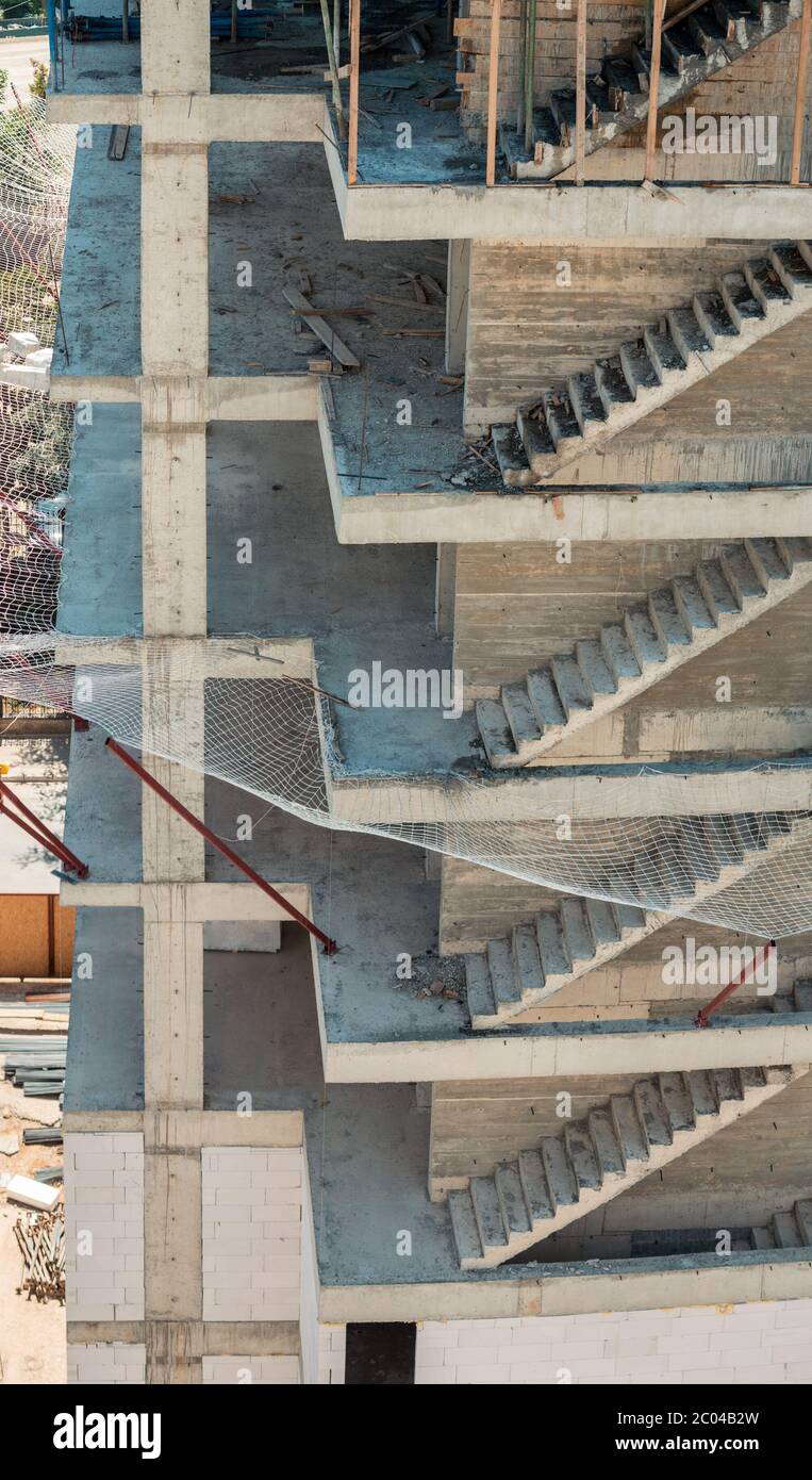 High angle view of a building under construction with unfinished concrete staircases and construction site safety net which can sustain heavy jerks. Stock Photo