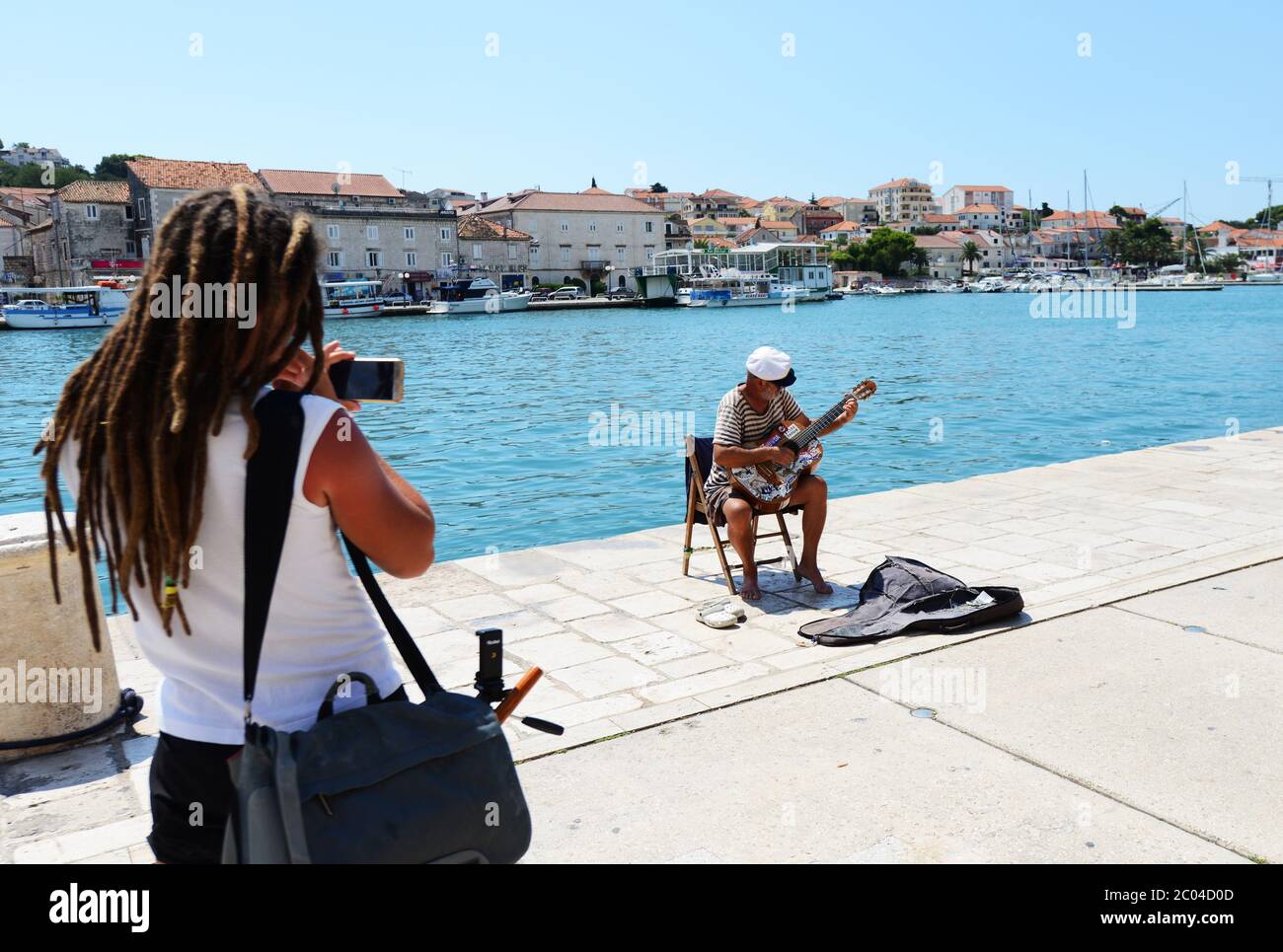 A tourist filming a  local busker in Trogir, Croatia. Stock Photo