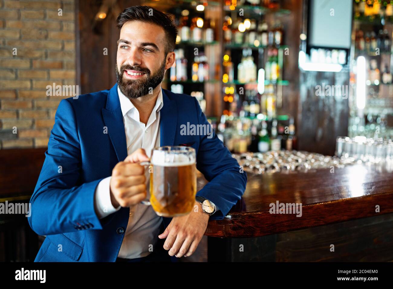 Handsome young man is drinking beer in bar and smiling Stock Photo - Alamy