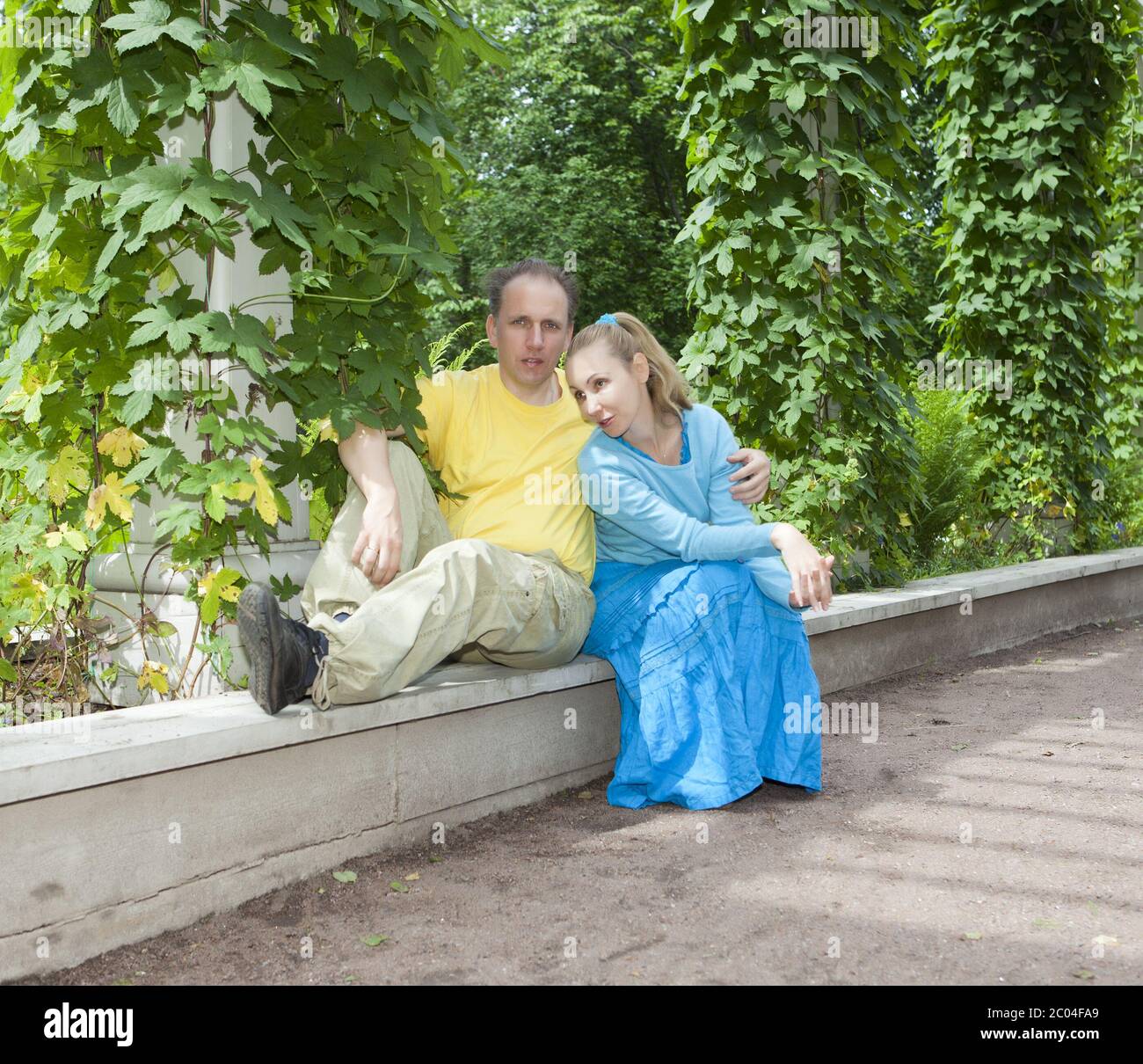 couple sits in the arbour twined greens Stock Photo