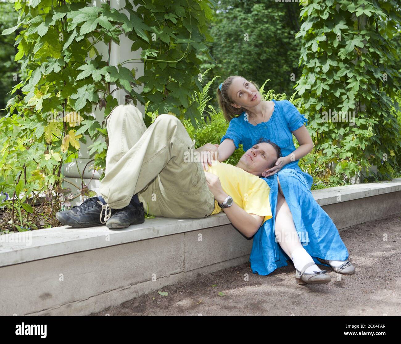 happy couple sits in the arbour twined greens Stock Photo