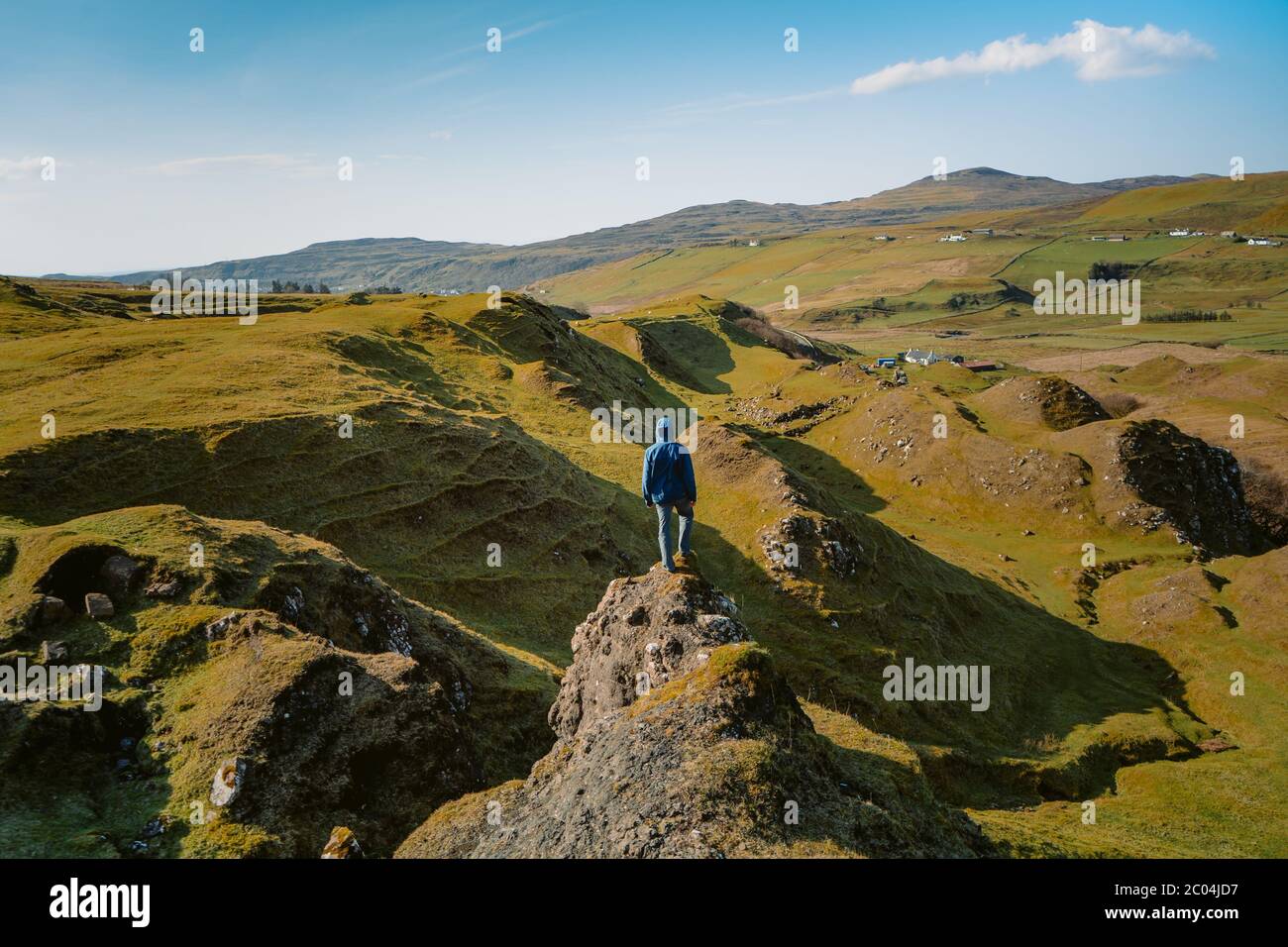Lone man stands atop mound, overlooking the stone pillars, shapes and circles below. Picture taken at Fairy Glen, in the Isle of Skye, Scotland. Stock Photo