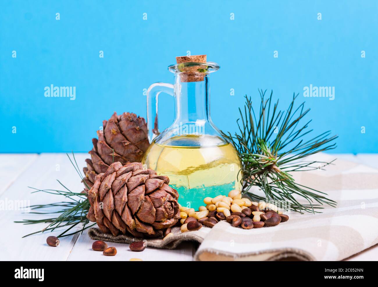 composition, cedar oil with cones and nuts on a white wooden table on a blue background Stock Photo