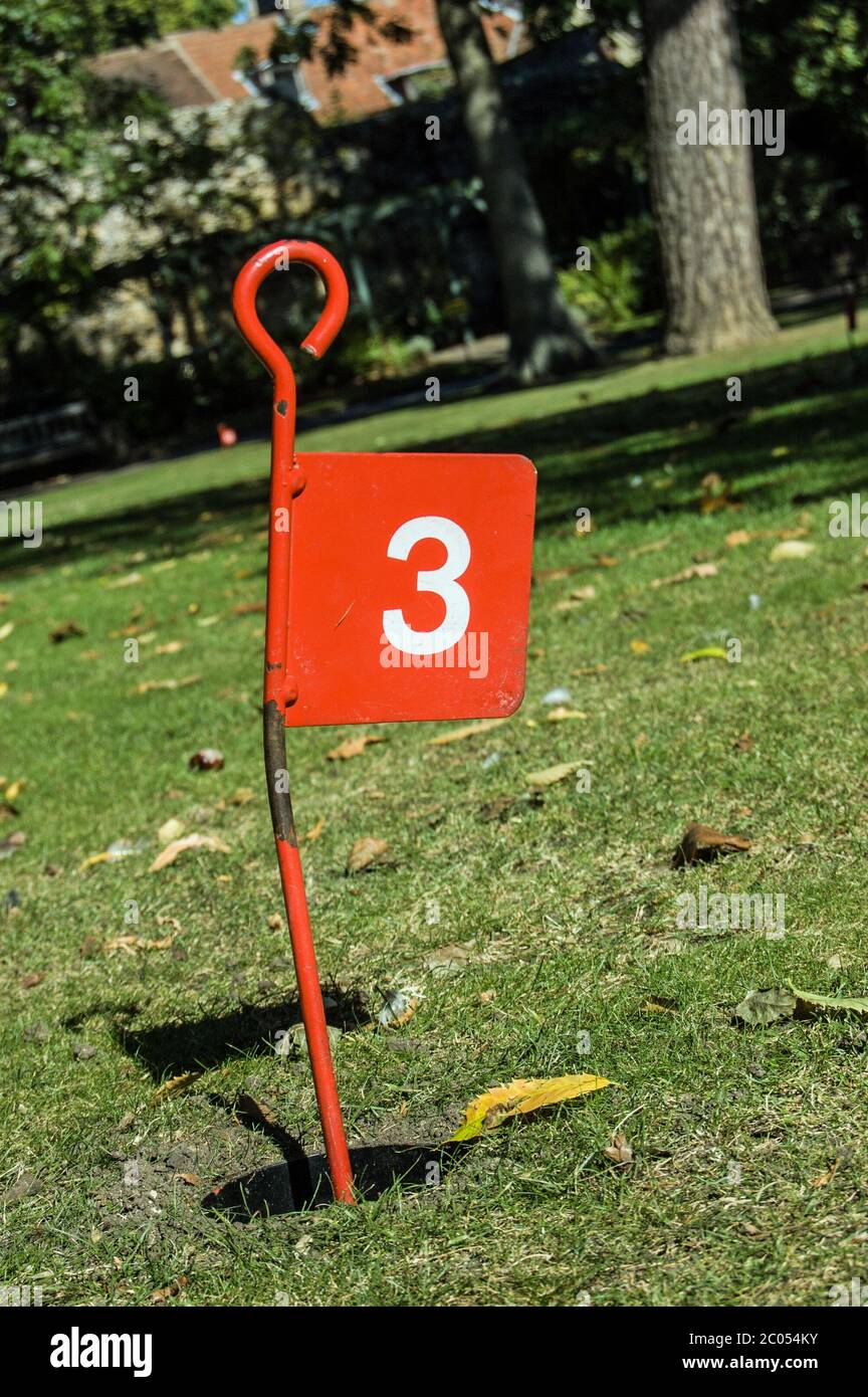A red metal flag sign at golf hole number three on the mini golf course at  Abbey Gardens, Bury St Edmunds, Suffolk Stock Photo - Alamy
