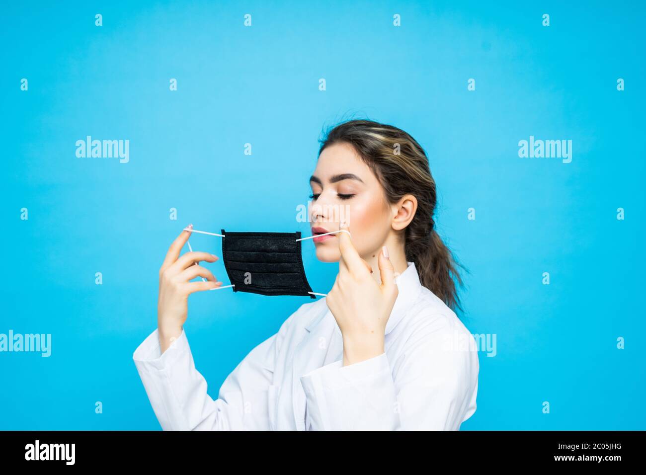 Young woman in a urgical suit, wears a protective mask on her face and ...