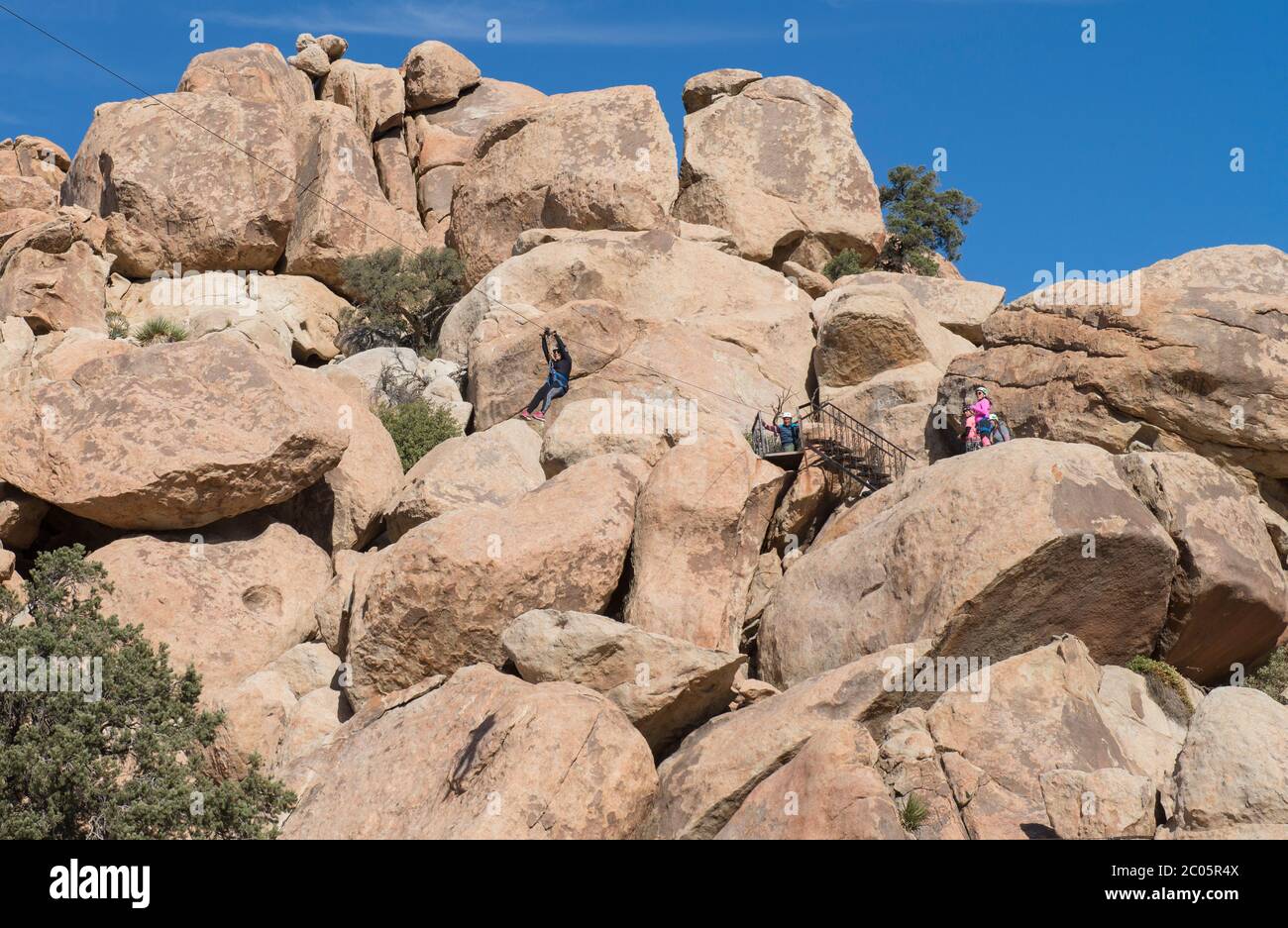 People in the mountains enjoying a zip line in La Rumorosa mountains, as part of a lifestyle and extreme sports concept. Baja California, Mexico. Stock Photo