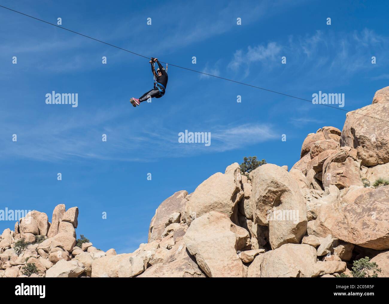 People in the mountains enjoying a zip line in La Rumorosa mountains, as part of a lifestyle and extreme sports concept. Baja California, Mexico. Stock Photo