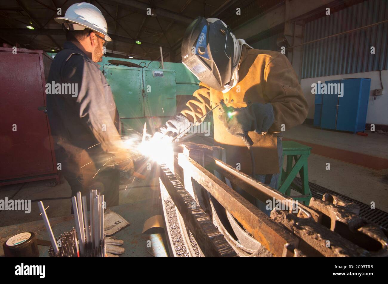 Employees in a Geothermal power plant performing welding jobs and a training program in the mechanic workshop as part of a skilled job apprentice plan. Stock Photo